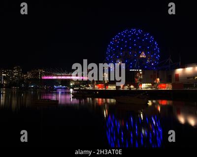 Atemberaubende Nachtansicht der False Creek Bay mit Vancouver Science World und BC Place Stadium, die sich im ruhigen Wasser mit der beleuchteten Skyline spiegeln. Stockfoto