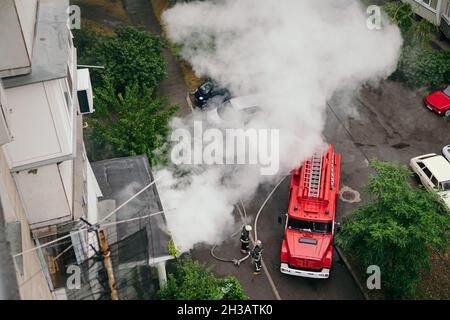 Feuerwehrleute kamen in Feuerwehrautos in das Wohnhaus in der Großstadt und löschen das Feuer. Stockfoto