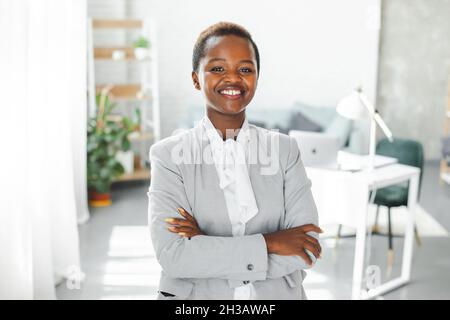 Porträt einer erfolgreichen afrikanerin, die lächelt und die Arme gekreuzt hält. Schöne afrikanische Frau. Stockfoto