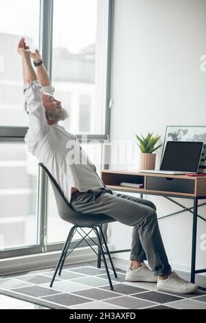 Ein reifer, selbstständiger Mann, der zu Hause arbeitet und müde aussieht Stockfoto