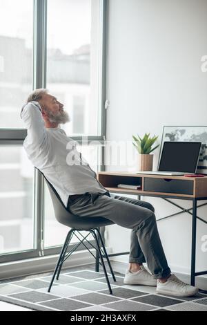 Ein reifer, selbstständiger Mann, der zu Hause arbeitet und müde aussieht Stockfoto