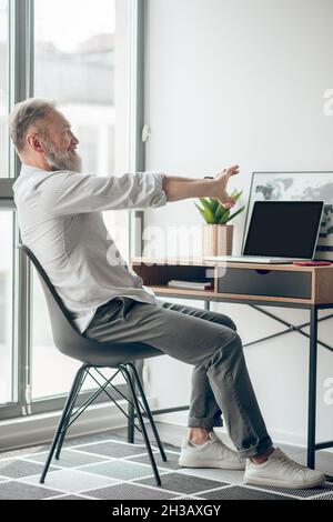 Ein reifer, selbstständiger Mann, der zu Hause arbeitet und müde aussieht Stockfoto