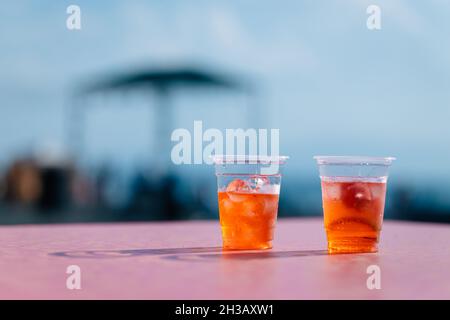 Frische Orangencocktails in Plastikbechern auf dem Tisch während einer Strandparty im Sevan-See, Armenien Stockfoto