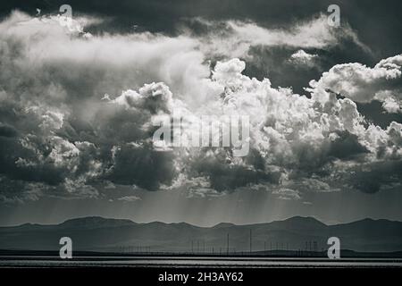 Einfarbige Aufnahme von Sonnenlicht, das durch dramatische Wolken über dem Sevan-See in Armenien bricht Stockfoto