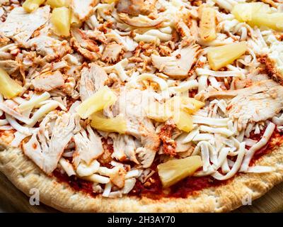 Gefrorene Pizza mit Hähnchenscheiben und Ananasstücken aus nächster Nähe Stockfoto