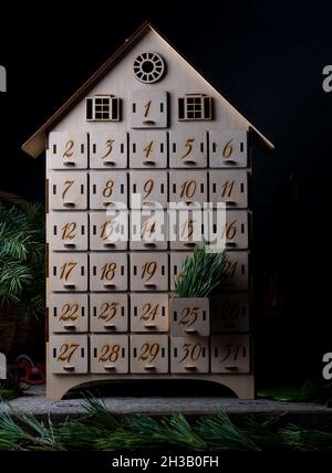 Holzadventkalender für das Warten auf Neujahr oder weihnachten. Box mit Zellen von 1 bis 25 und 31 für Mini-Geschenke. Dezember-Atmosphäre und Einrichtung Stockfoto