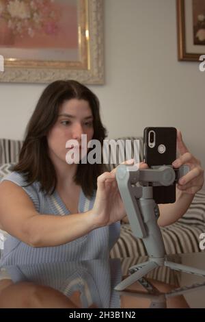 Junge Bloggerin Mädchen, das Handy auf Stativ, um tägliche Blog aufzeichnen Blick auf ihre Handy-Kamera. Online-Videoblog für soziale Medien. Stockfoto