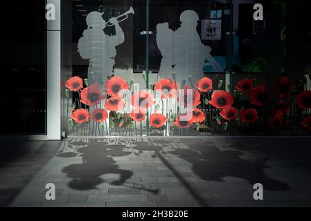 London, Großbritannien. 27. Oktober 2021. Schatten, die von einer Mohn-Ausstellung im Fenster des Hauptquartiers der Versicherungsgesellschaft Aviva in der City of London geworfen werden. Der Gedenktag am 11. November erinnert jedes Jahr an die Mitglieder der Streitkräfte, die im Rahmen ihrer Dienstzeit ihr Leben verloren haben. In Großbritannien sind Mohnblumen in der Regel ein Symbol der Erinnerung. Kredit: Stephen Chung / Alamy Live Nachrichten Stockfoto