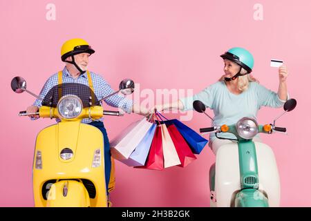 Foto von ziemlich süß Großmutter Großvater Reiten Motorrad Helme halten Schnäppchen Kreditkarte isoliert rosa Farbe Hintergrund Stockfoto