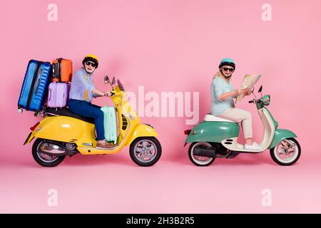 Seitenfoto der lustigen Großmutter Großvater Reiten Motorrad Helme mit Koffern suchen Karte isoliert rosa Hintergrund Stockfoto