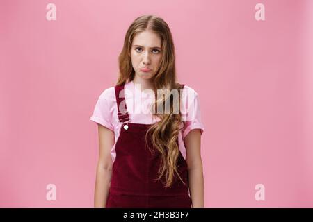 Porträt von albern unzufrieden und unwohl nette junge Frau in Overalls Pouting und schmollend machen düstere Gesicht zu verlieren oder mit schlechten Tag stehen aufgeregt Stockfoto