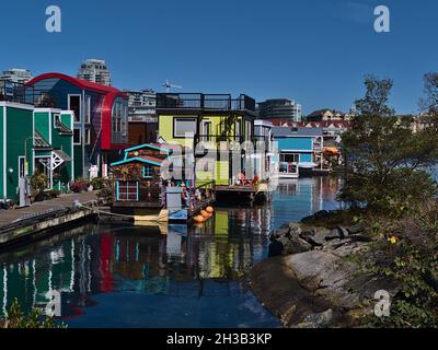 Bunte schwimmende Häuser von Fisherman's Wharf im Victoria Harbour, Vancouver Island an sonnigen Herbsttag mit Reflexen auf der Wasseroberfläche. Stockfoto