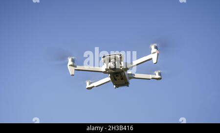 Weiße Drohne, die auf dem Hintergrund der Natur fliegt. Drohne hängend in der Luft Flughubschrauber Drohne Fernbedienung Luftdrohne Stockfoto