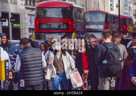 Menschen, die während der Coronavirus-Pandemie auf einer belebten Oxford Street Schutzmasken tragen. London, Großbritannien, 26. Oktober 2021. Stockfoto