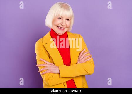 Foto von optimistischen ziemlich kurze Frisur reife Dame gekreuzte Arme tragen gelbe Jacke auf lila Hintergrund isoliert Stockfoto