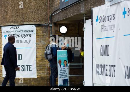 Banner einer Covid-Impfstelle sind vor einer Apotheke zu sehen, als Menschen am 23. Oktober 2021 in London eintreffen. Stockfoto