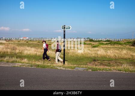 Menschen Mann und Frau Paar Wanderer Wanderer gehen entlang der Straße in der Landschaft in der Nähe des Kernkraftwerk Dungeness in Kent England, Großbritannien KATHY DEWITT Stockfoto