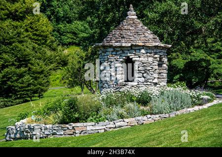 Kleiner, aus Stein gegliederter Pavillon mit Blumengarten und Steinmauer auf dem Gelände des Mohonk Mountain House im Bundesstaat New York. Stockfoto