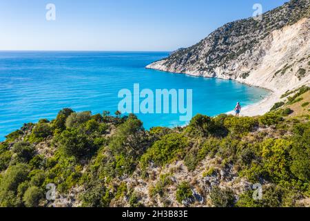 Mann Tourist, der auf einem Felsen steht und Myrtos Beach genießt. Insel Cefalonia, Griechenland Stockfoto
