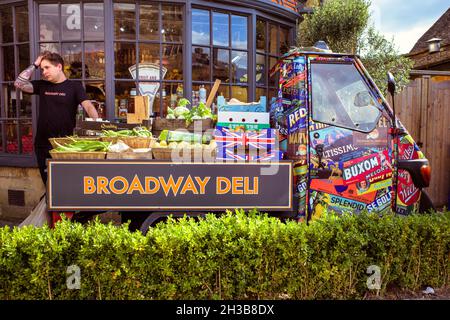 Ein Mann, der Gemüse von einem kleinen Lastwagen vor einem Delikatessengeschäft in Broadway, den Cotswolds, Großbritannien, verkauft. Stockfoto