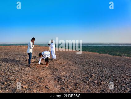 Kahartum, Sudan, ca. 5. Februar 2019: Junge sudanesische Männer aus reicher Familie sammeln Steine auf dem Hochplateau des heiligen Berges Jebel Barkal Stockfoto