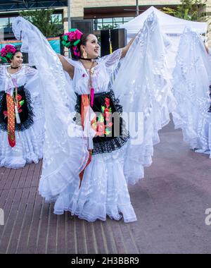 10-09-2021 Tulsa USA -die schöne junge hispanische Tänzerin hält uns die Röcke von weißen Spitzen-Röcken traditioneller Kostüme, während wir in der Straße tanzen.j Stockfoto