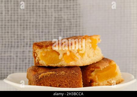 Drei Portionen Pfirsichkuchen, in die die Pfirsichstücke gelegt wurden. Stockfoto