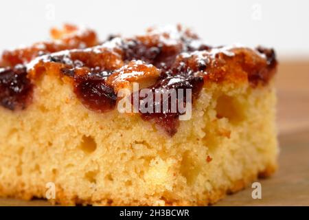 Auf der Planke liegt ein kleines Stück Kirschkuchen, der mit Gießzucker bestreut wurde. Stockfoto