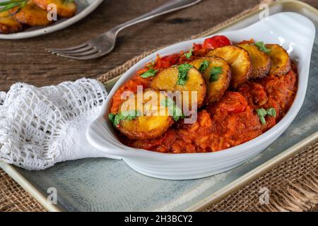 Reisjollof mit frittiertem Kochbananen - würziges vegetarisches afrikanisches Reisgericht Stockfoto