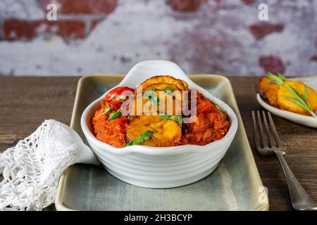 Reisjollof mit frittiertem Kochbananen - würziges vegetarisches afrikanisches Reisgericht Stockfoto