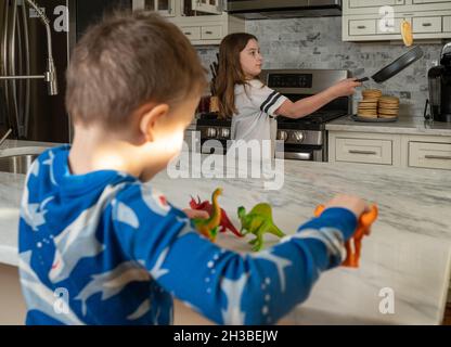 Bruder und Schwester in einer modernen Küche Pfannkuchen drehen Stockfoto