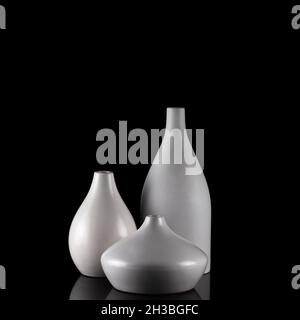 Drei kurvige weiße Vasen auf schwarz, mit Spiegelung. Stockfoto