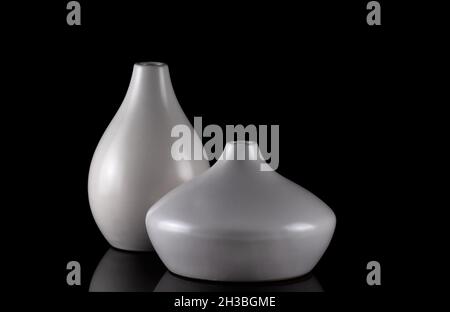 Zwei kurvige weiße Vasen auf schwarz, mit Spiegelung. Stockfoto