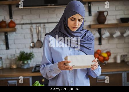 Muslimische Frau hält ein Tablett mit Eiern in ihrer Küche Stockfoto