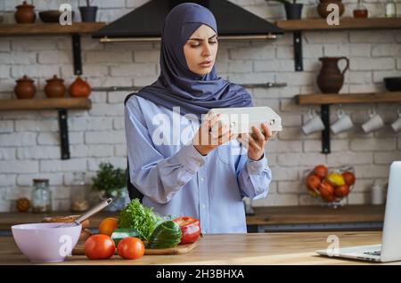 Muslimische Dame, die ein Tablett mit Eiern hält und nach einem Ablaufdatum sucht Stockfoto