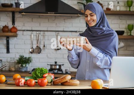 Wunderschöne muslimische Frau, die ein Tablett mit Eiern hält und lächelt Stockfoto