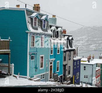 St. John's, NL, Kanada-Oktober 2021: Mehrere bunte Holzhäuser, auf einer Straße mit einem leichten Hügel. Es gibt Dachgauben und Hüftdächer. Stockfoto