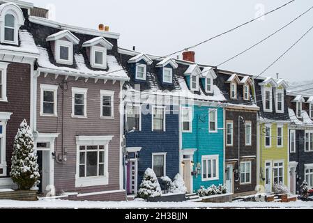 St. John's, NL, Kanada-Oktober 2021: Mehrere bunte Holzhäuser, auf einer Straße mit einem leichten Hügel. Es gibt Dachgauben und Hüftdächer. Stockfoto