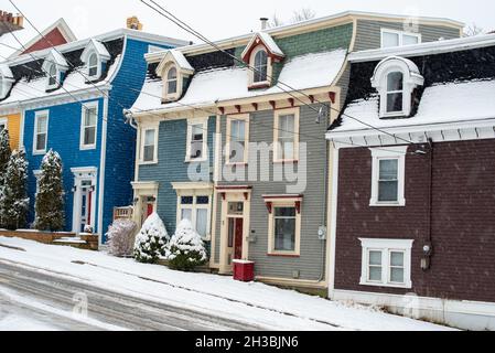 St. John's, NL, Kanada-Oktober 2021: Mehrere bunte Holzhäuser, auf einer Straße mit einem leichten Hügel. Es gibt Dachgauben und ein Hüftdach. Stockfoto