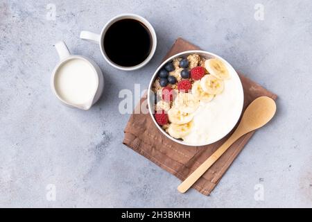 Gesundes Frühstück auf grauem Hintergrund. Das Konzept der leckeren und gesunden Lebensmittel. Müsli, Kaffee und Milch. Draufsicht, Kopierbereich. Stockfoto