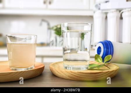 Vergleich von Schmutzwasser und durch Osmose in Gläsern auf einer Küchenbank mit Filter und Ausrüstung im Hintergrund gefiltert. Vorderansicht. Horizontales CO Stockfoto