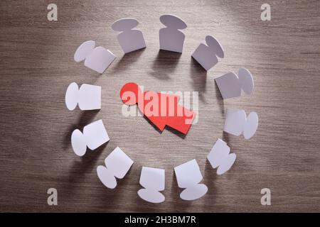 Konzept des Todes einer Frau durch geschlechtsspezifische Gewalt und sozialen Druck mit Ausschnitt der Frau auf dem Tisch liegen und Gruppe von Männern herumstehen. Stockfoto