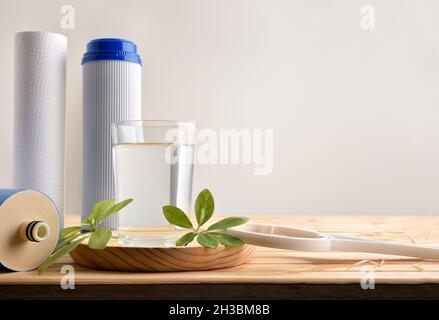 Glas von gereinigtem Wasser mit Haushaltsgeräten und umweltfreundlichen Filtern auf Holztisch isoliert Hintergrund mit Osmotizer Ausrüstung. Fro Stockfoto