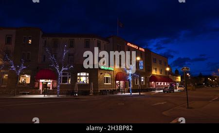 Schöner Blick auf die Innenstadt von Jasper in den kanadischen Rocky Mountains mit historischem Athabasca Hotel, leerer Straße und beleuchteten Bäumen im Herbst. Stockfoto