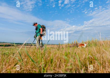 Ein Mann mit Panamahut und Rucksack läuft mit einem Metalldetektor. Stockfoto