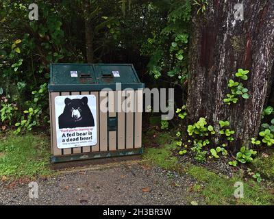 Bärensichere Mülltonne am Wild Pacific Trail in Ucluelet, Vancouver Island im Wald mit großen Bäumen und Informationsschild. Stockfoto