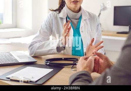 Doctor sitzt mit Rezept am Schreibtisch und hat ein Gespräch mit ihrer Patientin Stockfoto