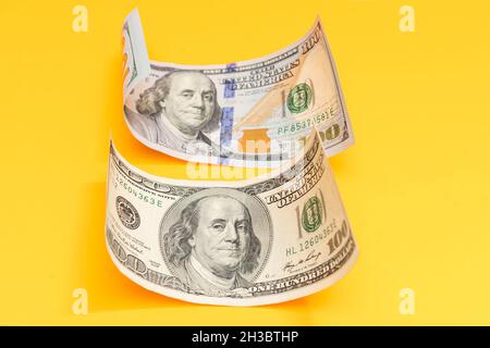 Einhundert-Dollar-Bill rollte auf Gelb Stockfoto