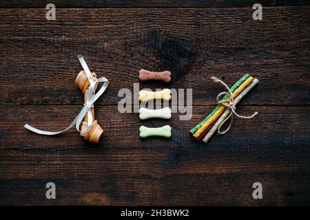 Hundeknochen in Schale auf Holzhintergrund. Künstliche Knochen und Mini kleine Leckereien für Haustiere. Langlebige Hundekauen Knochen und Snacks Stockfoto