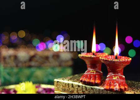 Tonlampe bekannt als Diya, Deep, Diyo, Deepa oder Deepam mit Göttin Füße Lakshmi Charan beleuchtet auf Golden Gift Box mit Bokeh Effekt. Shubh Deepawa Stockfoto